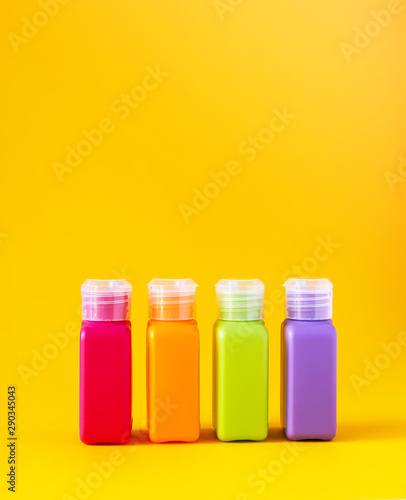 Colorful plastic bottles for skincare products or different purposes on yellow background