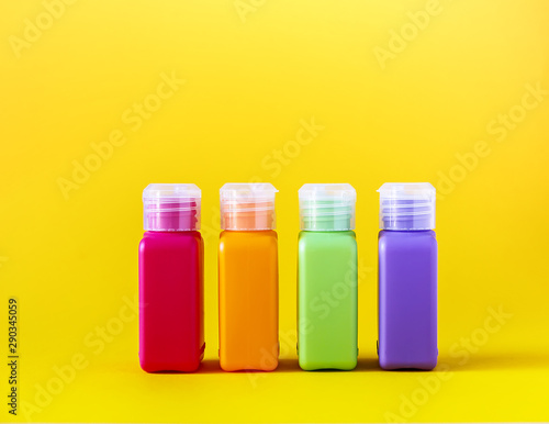 Colorful plastic bottles for skincare products or different purposes on yellow background