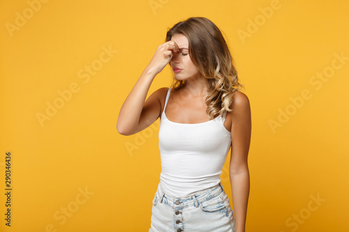 Exhausted young woman girl in light casual clothes posing isolated on yellow orange background studio portrait . People lifestyle concept. Mock up copy space. Keeping eyes closed putting hand on nose.