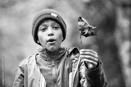 Boy with a leaf b&w portrait, autumn, child playing with fallen leaves in a park. Antonin, Poland. photo