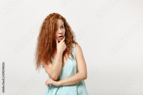 Young amazed redhead woman girl in casual light clothes posing isolated on white background, studio portrait. People lifestyle concept. Mock up copy space. Put hand prop up on chin, looking aside.