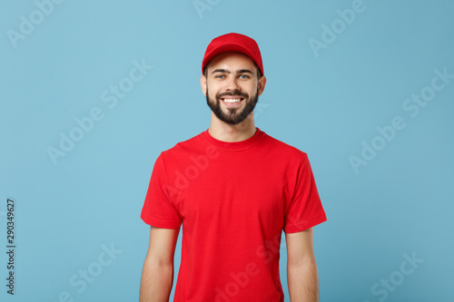 Delivery man in red uniform workwear isolated on blue wall background, studio portrait. Professional male employee in cap t-shirt print working as courier dealer. Service concept. Mock up copy space. photo