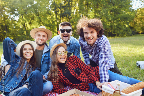 A group of people sitting on the grass on a picnic.