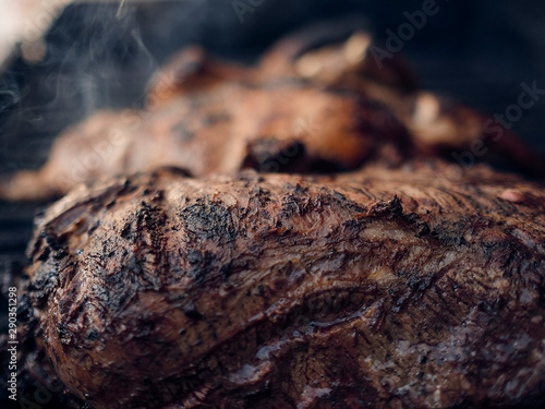 Grilled meats over the barbecue fire. You can see the smoke, the fire and the heat as well as the fiery ones of the melted fats when falling under the direct fire