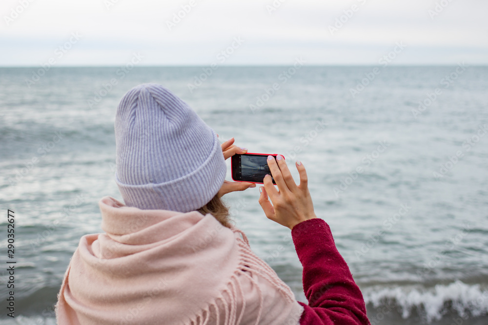 Girl photographs the sea on a smartphone