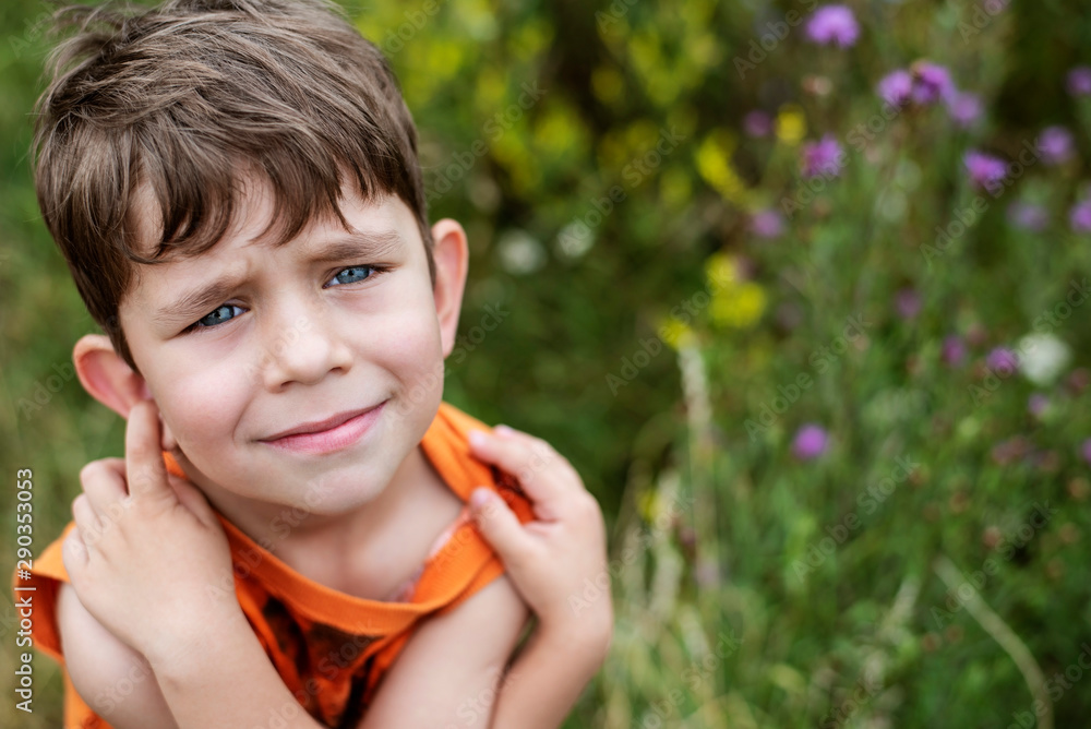 An authentic portrait of a young boy in nature, the boy hugs himself, tries to warm up and looks up. The boy has beautiful blue eyes An authentic portrait of a young boy in nature, the boy hugs himself, tries to warm up and looks up. The boy has beautiful blue eyes