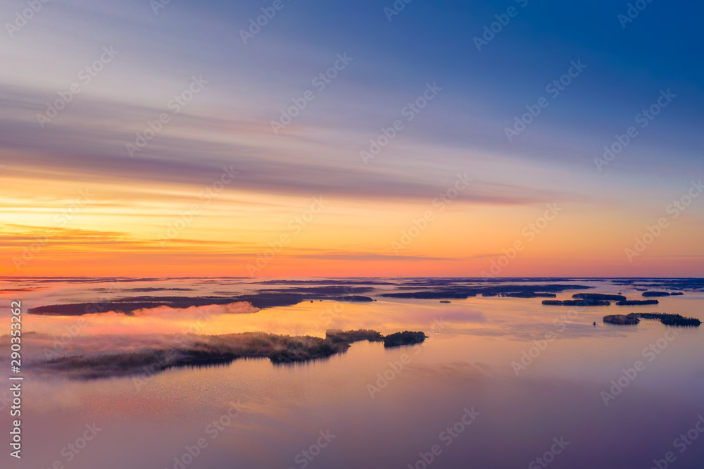 Long Exposure of Sunrise at the Paijanne lake. Beautiful scape with sunrise sky,fog, pine forest and water. Lake Paijanne, Finland.