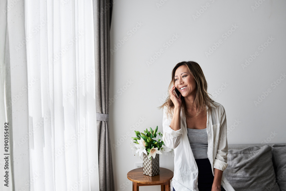 Beautiful Asian woman enjoying conversation by phone at home. Beautiful Asian woman enjoying conversation by phone at home.