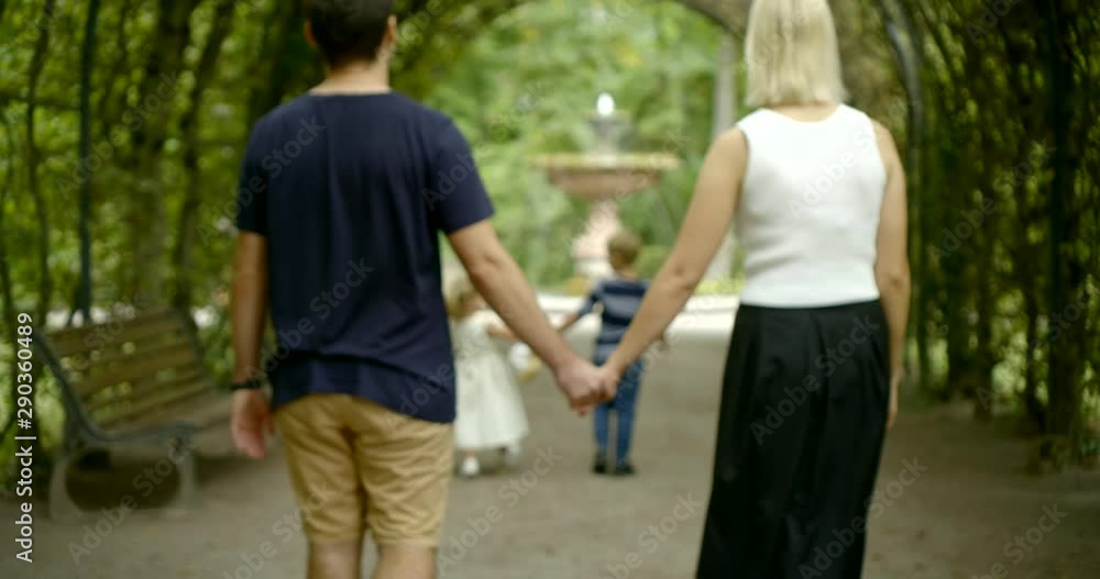 loving husband and wife are holding hands and walking in alley watching their children moving loving husband and wife are holding hands and walking in alley watching their children moving