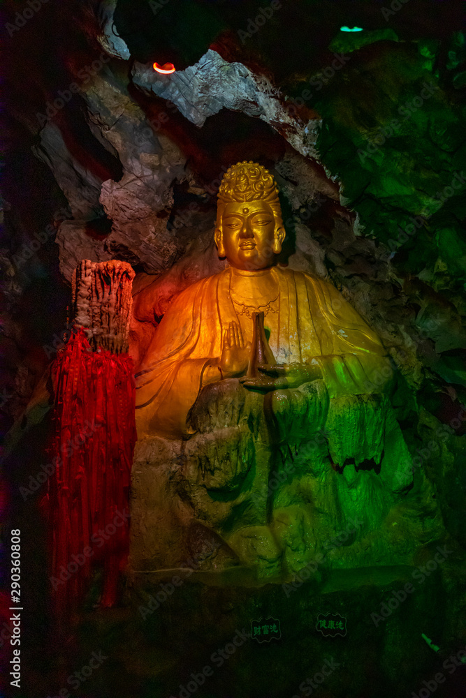 Beautiful illuminated multicolored Big Buddha in Danzhou Stone Flower Caves, Geopark next to Haikou, Hainan, China