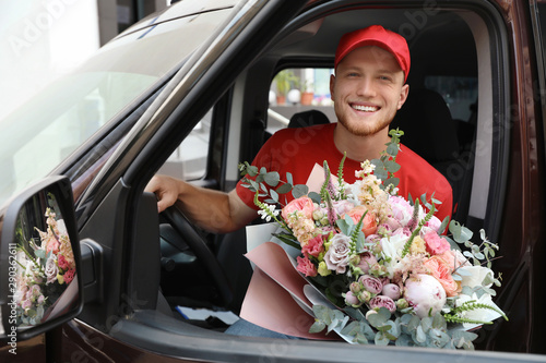 Delivery man with beautiful flower bouquet sitting in car