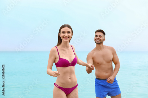 Young woman in bikini with her boyfriend on beach, space for text. Lovely couple © New Africa