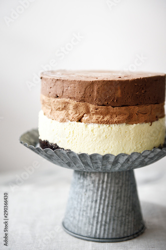Rustic three layer chocolate mousse cake on an industrial metal cake stand