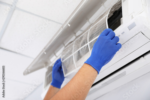 Professional technician maintaining modern air conditioner indoors  closeup