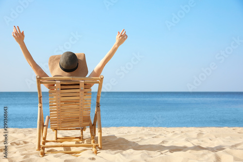 Young woman relaxing in deck chair on sandy beach