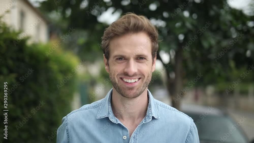 face a young happy casual man smiling, standing and then starts to walk, always looking at the camera face a young happy casual man smiling, standing and then starts to walk, always looking at the camera