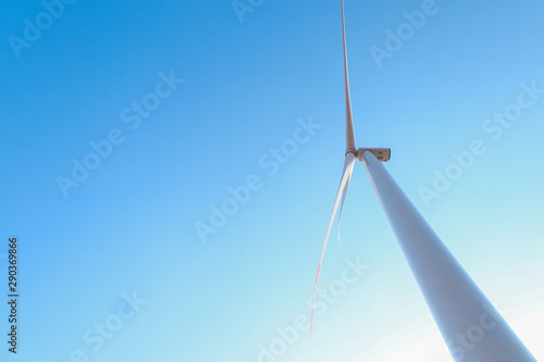 Looking upward to a big wind turbine and a blue sky. Alternative energy source, production and power generation. Ecology and freedom concept