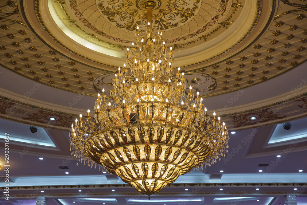 Obraz premium Gilded chandelier with burning candles in the Church. Large crystal chandelier in baroque style