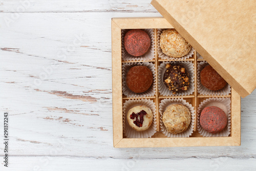 Assorted truffle set  of dark and white chocolate with almonds, hazelnuts and dried cranberries or cherries in a paper box. Candy.  Sweet gift. Holiday concept. Copy space, Selective focus