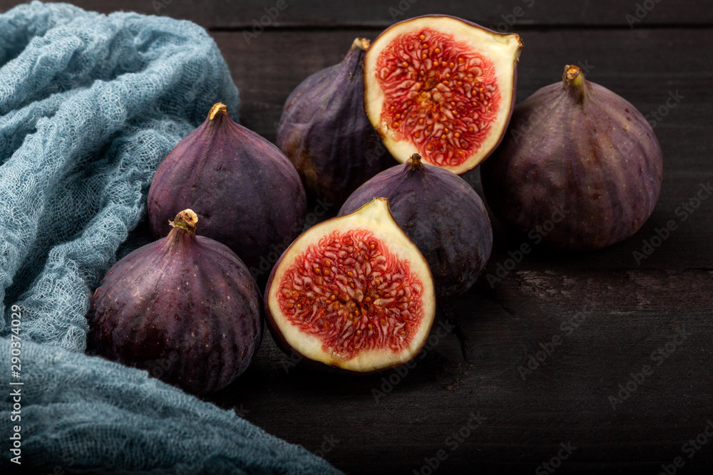 Fresh figs lie on a black wooden table. Beautiful blue fig fruits close up Fresh figs lie on a black wooden table. Beautiful blue fig fruits close up