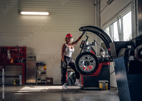 Manly sexy woman is taking man's profession - she is fixing broken car at auto service. photo