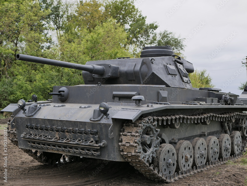 German medium tank of the Second World war in working order. the tank is painted black against a background of green trees in summer .