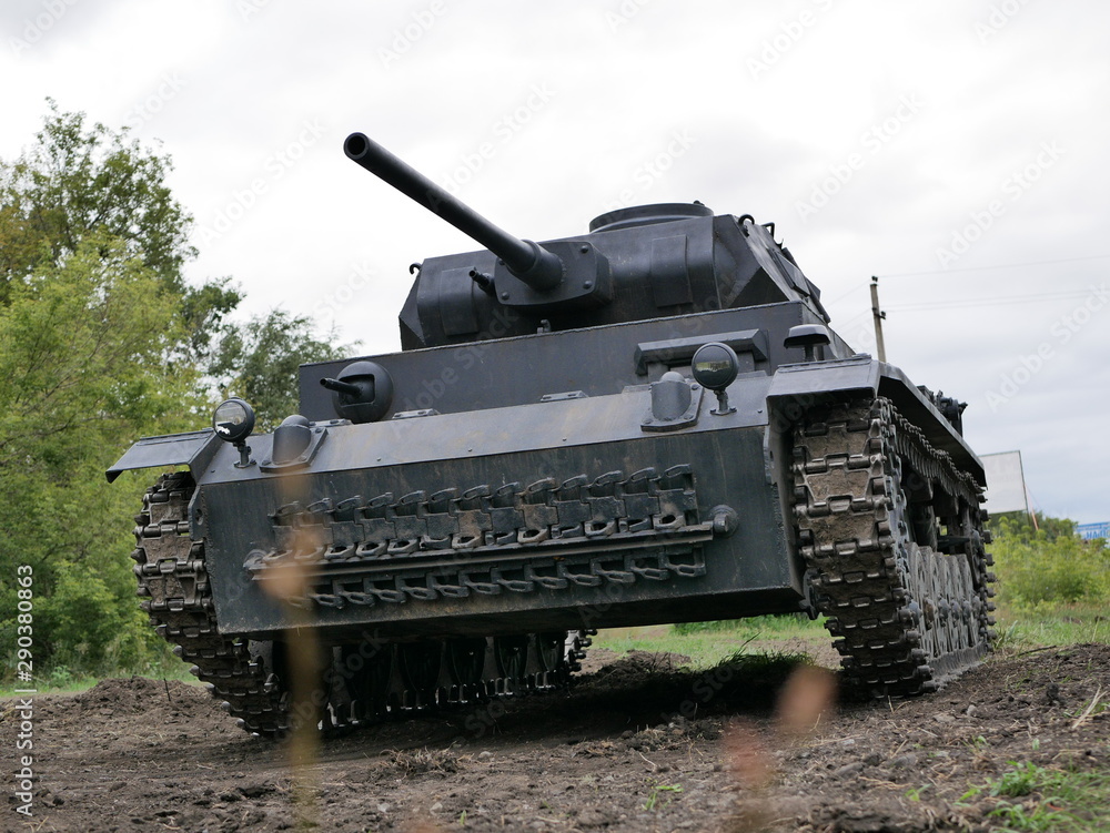 Fototapeta premium German medium tank of the Second World war in working order. the tank is painted black against a background of green trees in summer .