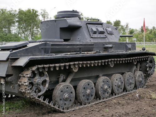 German medium tank of the Second World war in working order. the tank is painted black against a background of green trees in summer .