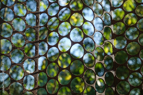 Fencing of a metal sheet with round holes against the blue sky. photo