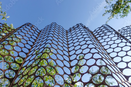 Fencing of a metal sheet with round holes against the blue sky.