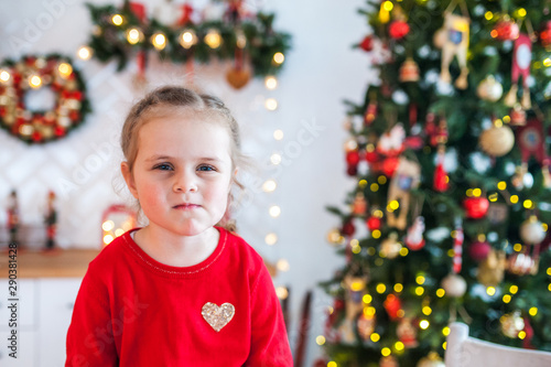 Portrait of a girl sitting in the kitchen decorated for Christmas