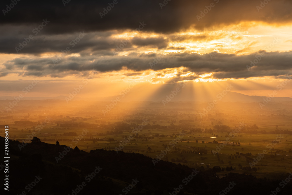 Amazing scenic sunset over endless rolling hills, villages and lakes. Beautiful sun rays peaking through the clouds. Colorful and vivid scene, peaceful and relaxing. Amazing scenic sunset over endless rolling hills, villages and lakes. Beautiful sun rays peaking through the clouds. Colorful and vivid scene, peaceful and relaxing.
