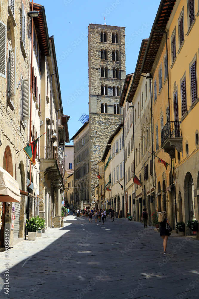 Arezzo, Tuscany, Italy. Street in old town of the medieval city, in background the bell tower of Santa Maria della Pieve also called torre dei cento buchi.