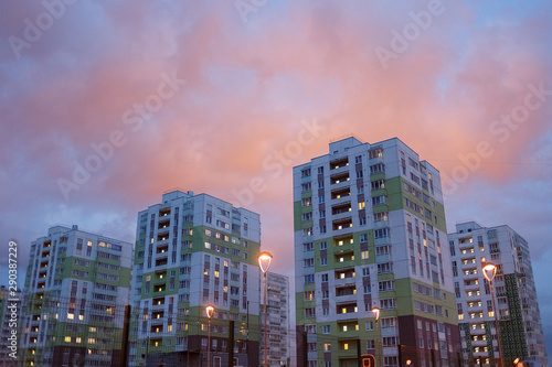 colorful houses on background of pink sunset in residential area. It's evening, lights burn in windows, lanterns lit up