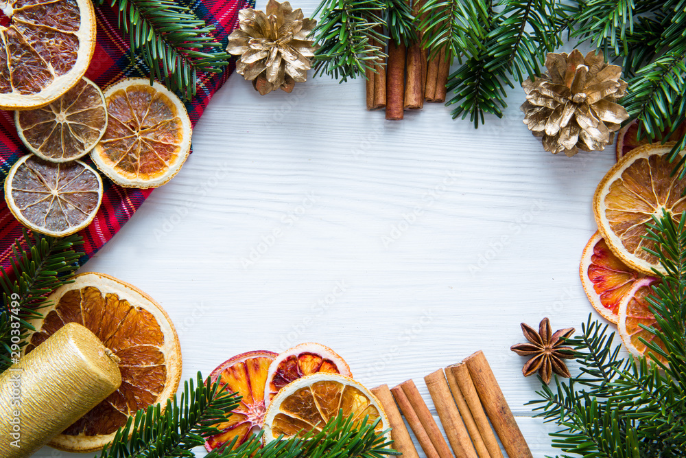 Christmas background frame with copy space. Dried oranges, golden cones, cinnamon sticks and candles on white wooden table, space for greeting. Christmas background frame with copy space. Dried oranges, golden cones, cinnamon sticks and candles on white wooden table, space for greeting.