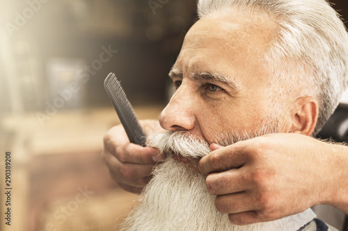 Canvas Print Handsome senior man getting styling and trimming of his beard