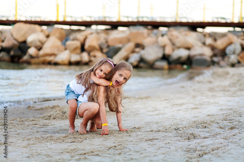 two little sisters having fun at the beach photo