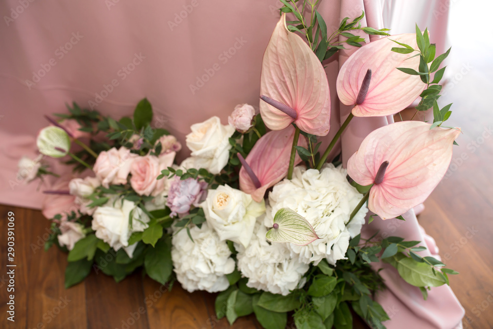 The wedding table setting for the newlyweds is decorated with fresh flowers of carnation, rose, anthurium and eucalyptus leaves. Silver candlesticks, white candles. Wedding floristry. Closeup details