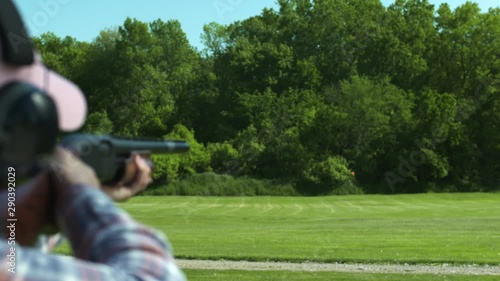 Slow motion over the shoulder, woman skeet shooting photo