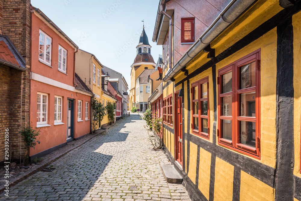 An alleyway with cobblestones and half timbered houses, leading up to the church in Faaborg