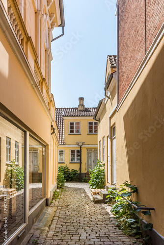 a narrow alley with yellow buildings on each side and the sky at the top in Faaborg, Denmark