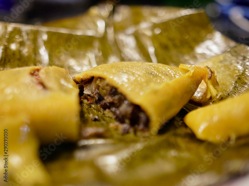 you can see a hallaca served in its banana leaf wrap. You can see The whole hallaca and also seen it cut in half photo