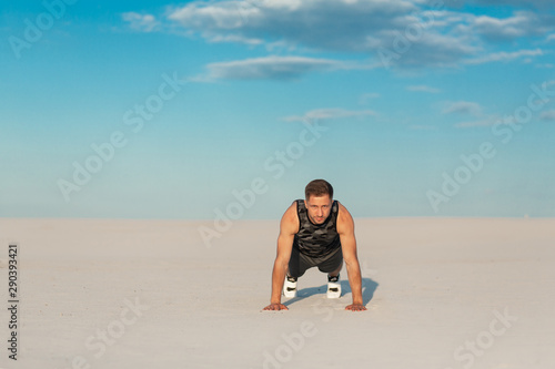 Fitness man doing exercises in sand desert. Sport concept.