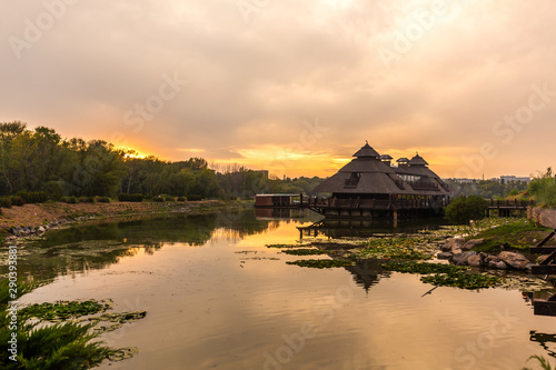 Sunset in a picturesque place. Wooden house near which a lake