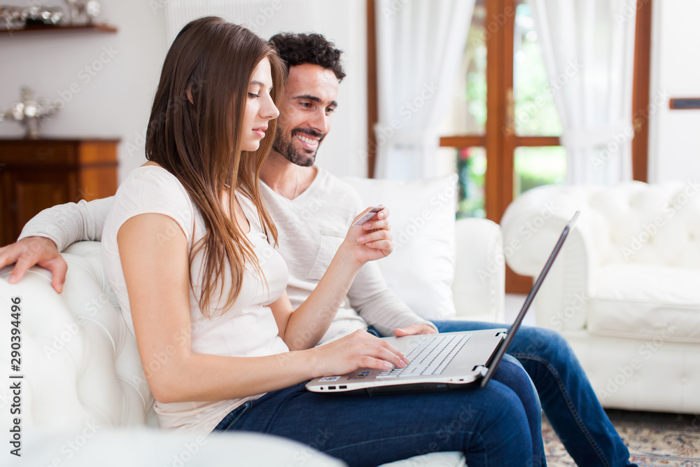Happy couple using a laptop on the sofa Happy couple using a laptop on the sofa