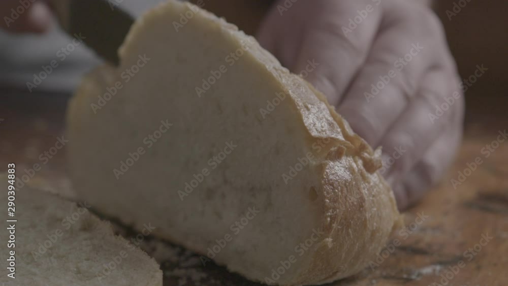 Close up, man cuts into bread loaf Close up, man cuts into bread loaf