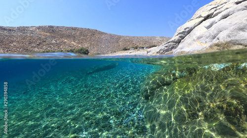 Above and below underwater photo of crystal clear turquoise pebble beach of Kaminakia  Astypalaia island  Dodecanese  Greece
