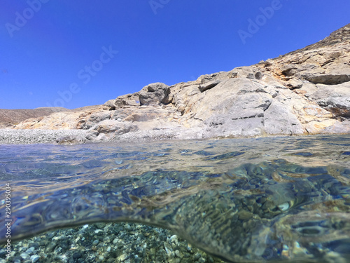 Above and below underwater photo of crystal clear turquoise pebble beach of Kaminakia, Astypalaia island, Dodecanese, Greece photo