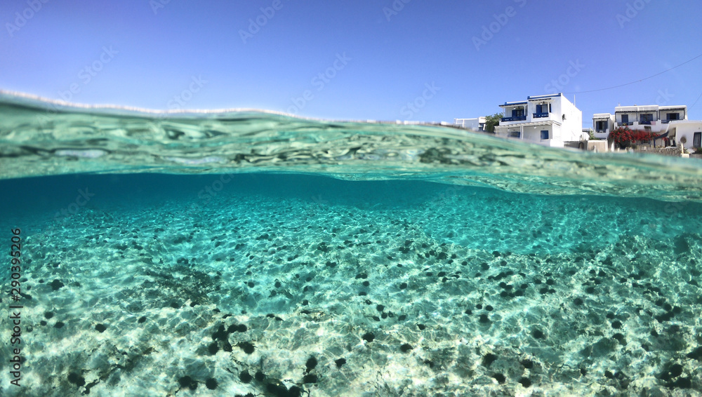 Above and below underwater photo of crystal clear turquoise sea paradise beach of Ammos and main town - port of Koufonisi island, Small Cyclades, Greece