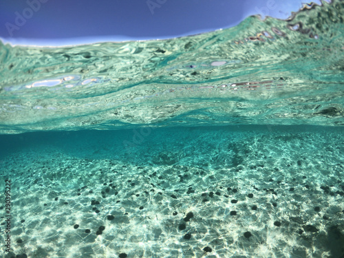 Above and below underwater photo of crystal clear turquoise sea paradise beach of Ammos and main town - port of Koufonisi island, Small Cyclades, Greece